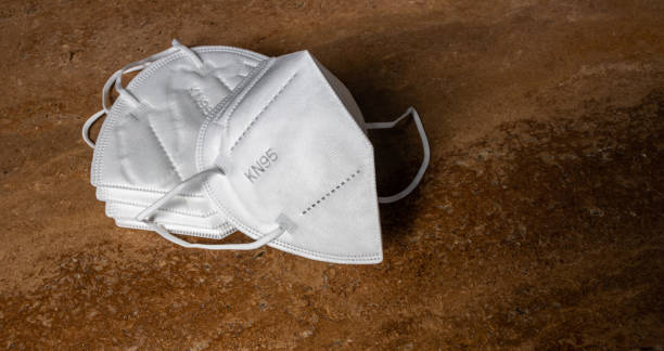 Face surgical white mask FFP2 KN95 N95 disposable for adults on travertine background. Masks are used to fight and prevent Coronavirus Covid-19 disease around the world